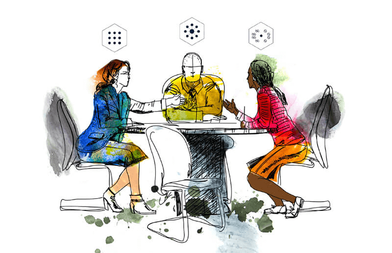 Two women and a man sitting at a round table.