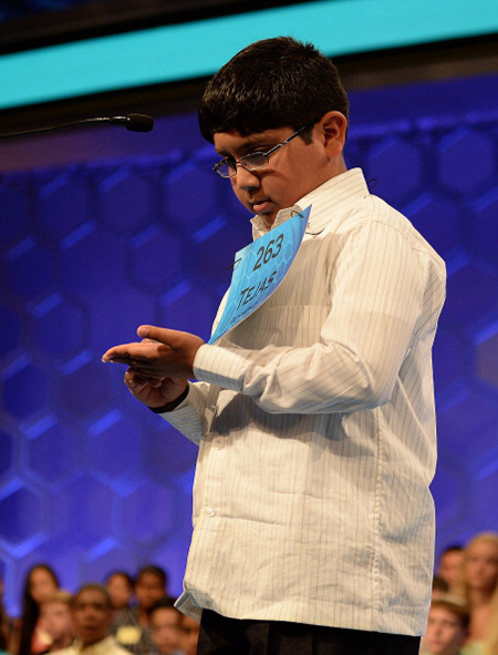 At the 2014 Scripps National Spelling Bee, Tejas Muthusamy executes his steadfast routine: asking for a word’s pronunciation, definition, origin and what part of speech it is; requesting use of the word in a sentence; querying for alternative pronunciations; repeating the word one last time; then, finally, spelling it with his finger on his hand.