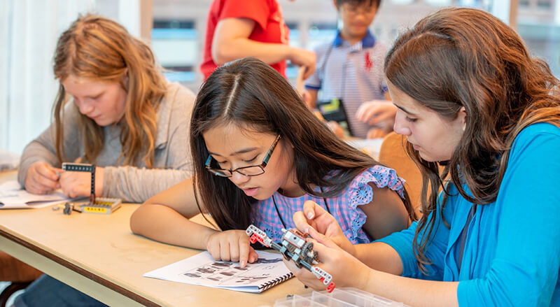 Two young girls working together to construct a airplane from Legos